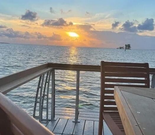 A sunset over the ocean with a wooden deck.